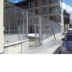 Clôture à barreaudage et portillon galvanisés devant une résidence