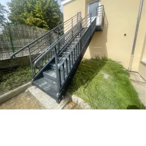 Escalier extérieur en acier avec garde-corps, posé le long d'un bâtiment