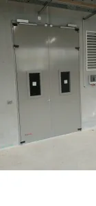 Porte métallique double vantail à hublots dans un local technique