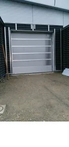 Porte sectionnelle industrielle posée sur un bâtiment à bardage